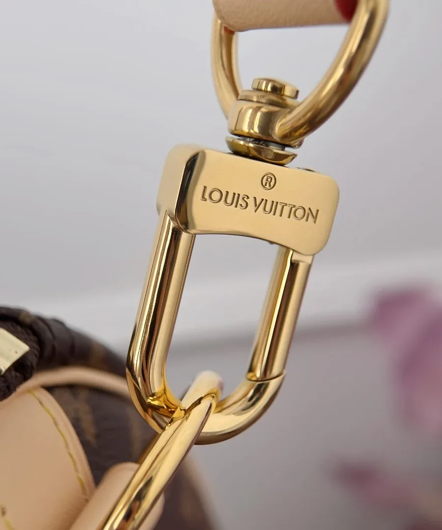 Крупный план золотистого карабина плечевого ремня с гравировкой Louis Vuitton