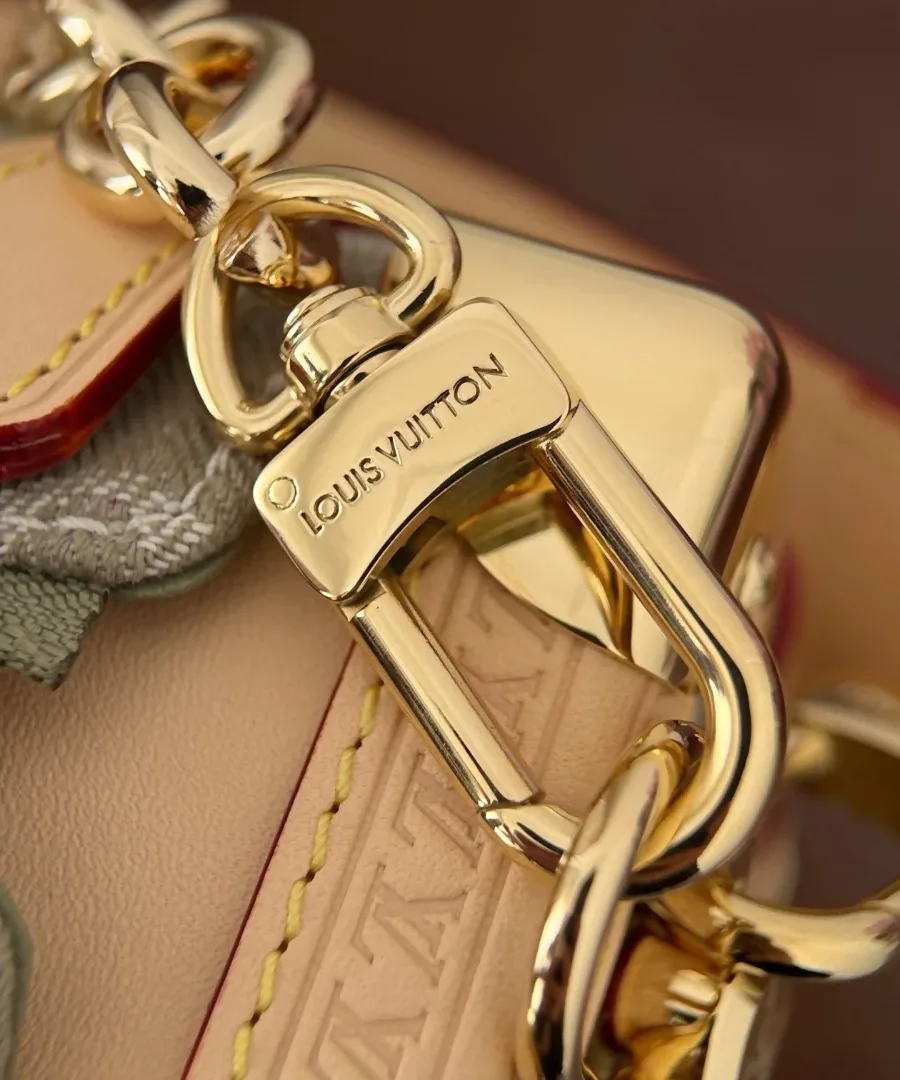 Крупный план золотистого карабина с гравировкой Louis Vuitton