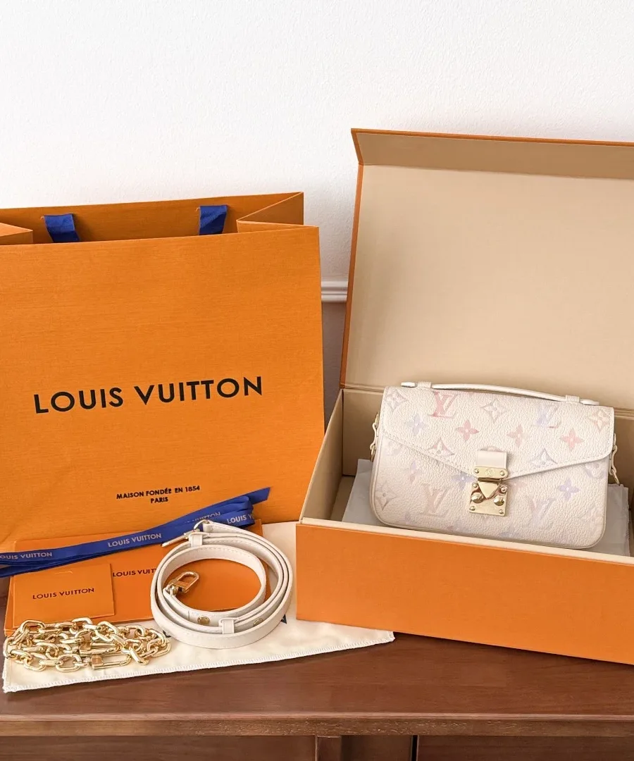 Сумка Pochette Métis East West в фирменной коробке рядом с оранжевым пакетом Louis Vuitton