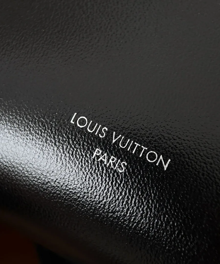 Крупный план серебристого тиснения Louis Vuitton Paris на черной коже