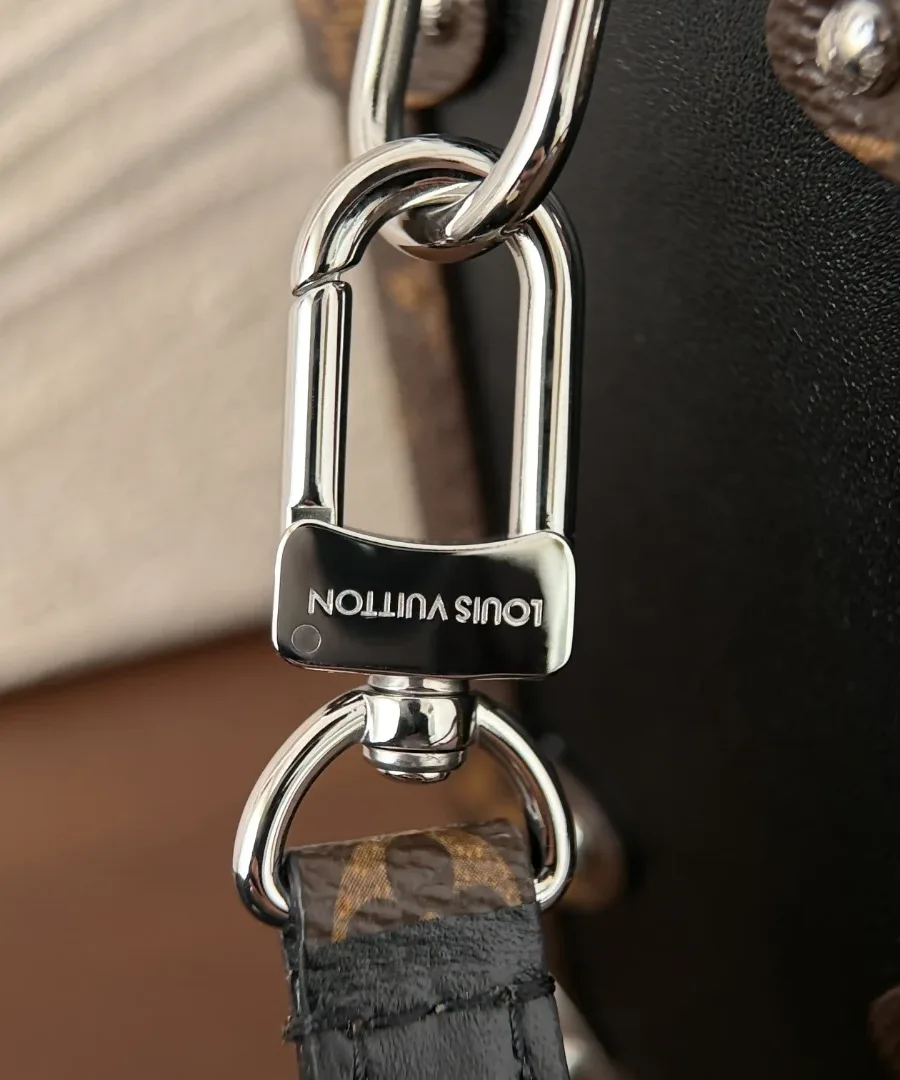 Крупный план серебристого карабина с гравировкой Louis Vuitton