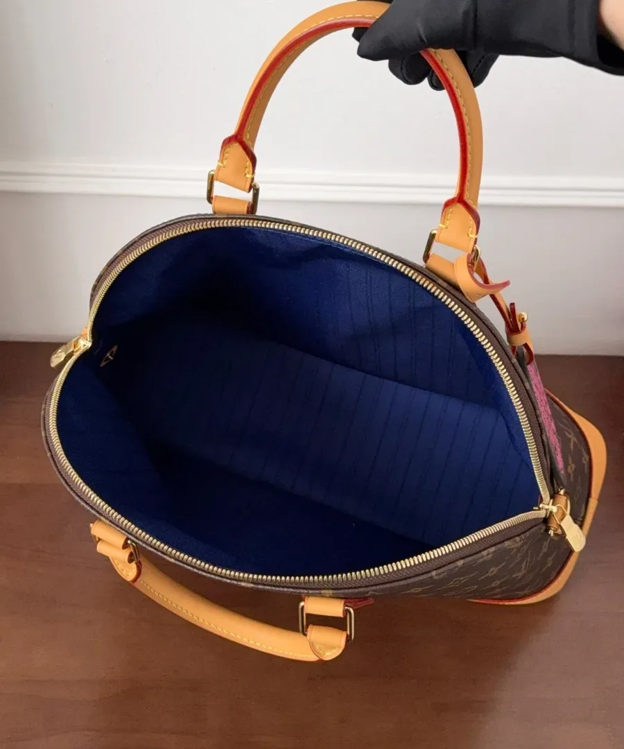 Сумка Louis Vuitton Alma Monogram в открытом виде, демонстрирующая синюю подкладку