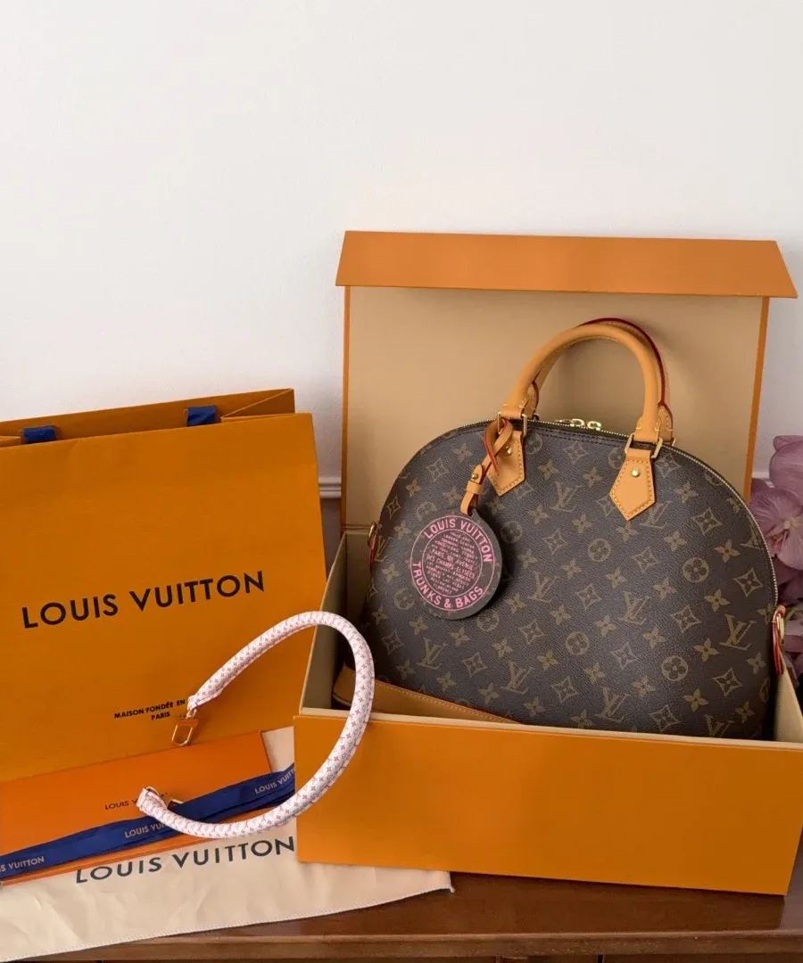 Сумка Louis Vuitton Alma Monogram рядом с фирменной коробкой и пакетом