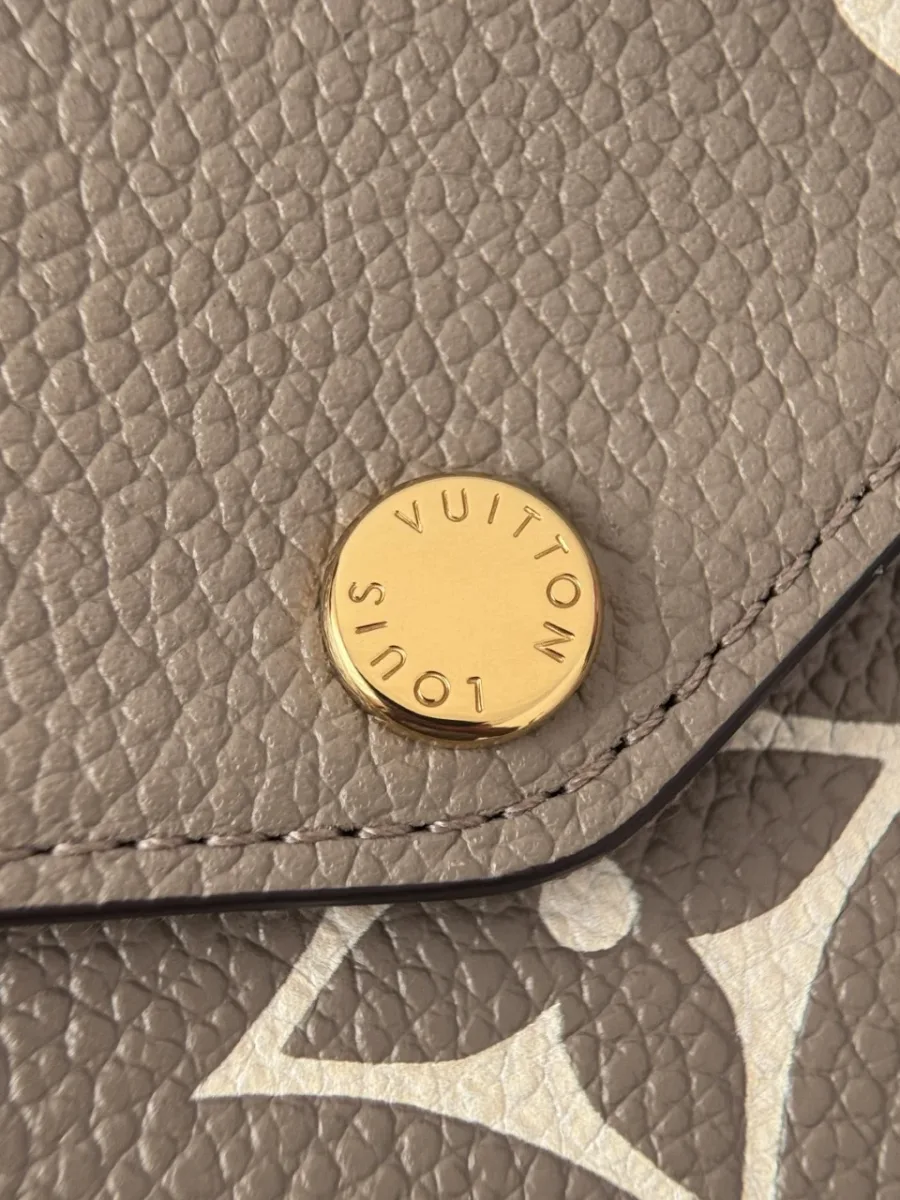 Крупный план золотистой кнопки-застежки с гравировкой Louis Vuitton