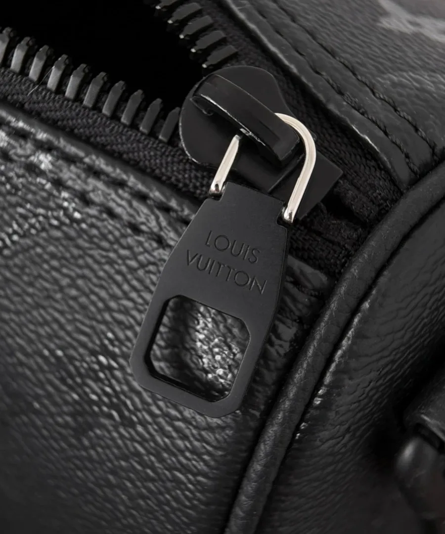Крупный план металлического пуллера молнии с гравировкой Louis Vuitton