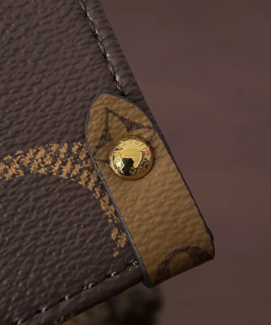 Крупный план угла сумки Louis Vuitton Onthego MM с золотистой заклепкой