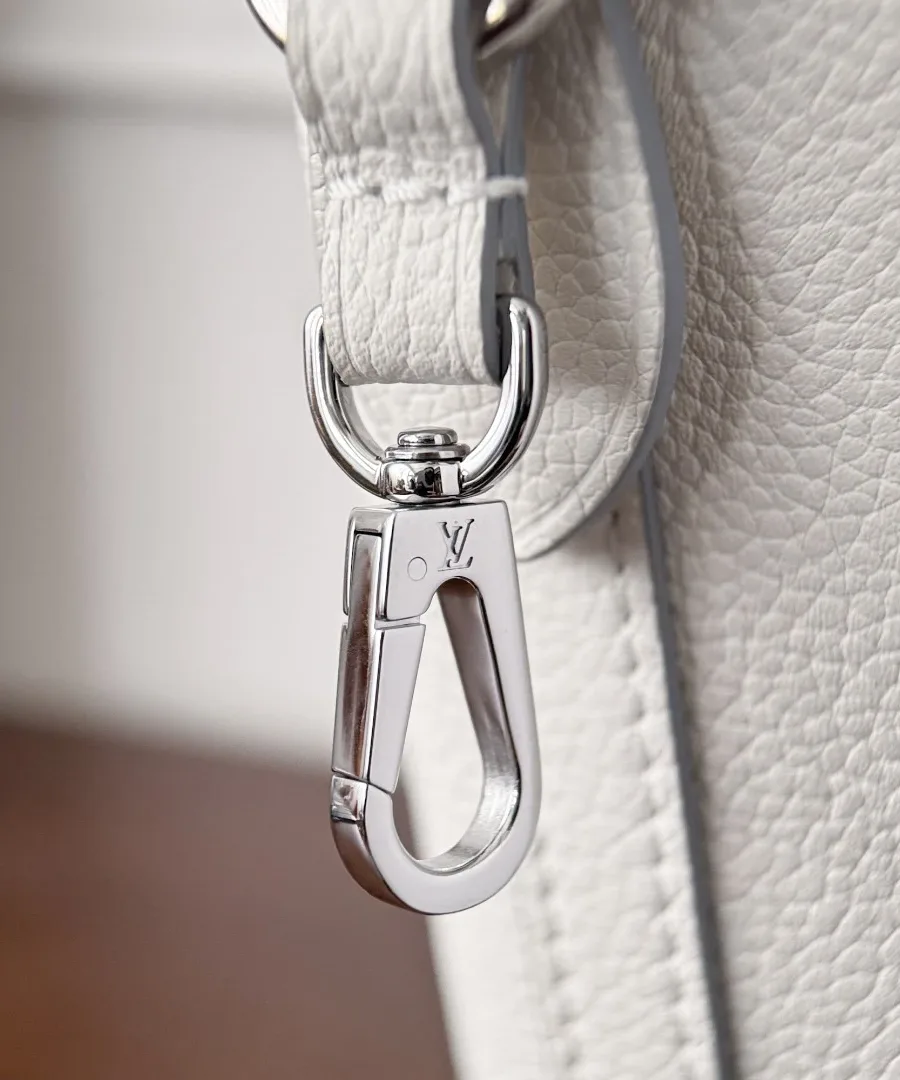 Крупный план серебристого карабина на плечевом ремне сумки Louis Vuitton