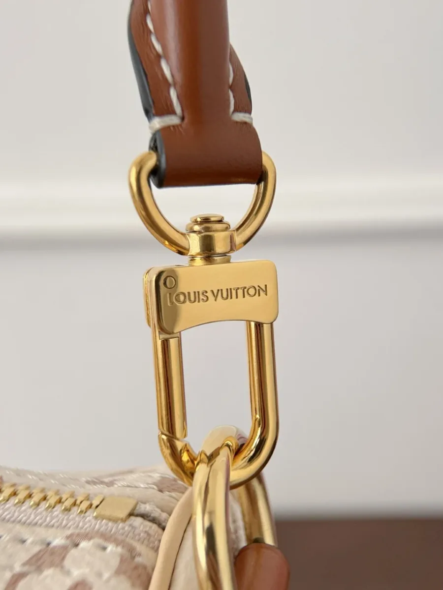 Крупный план золотистого карабина плечевого ремня с гравировкой Louis Vuitton