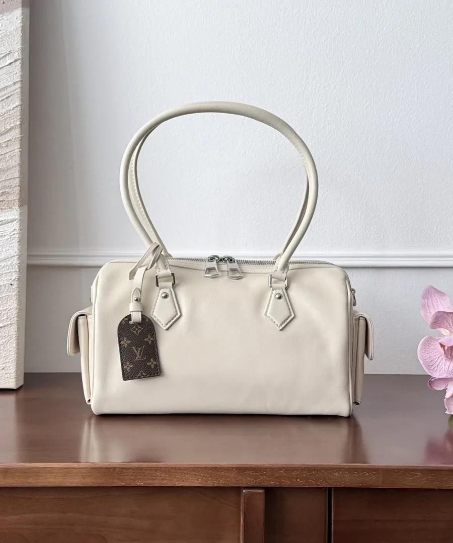 Бежевая сумка Speedy Cargo спереди, с багажной биркой Monogram, на деревянном столе