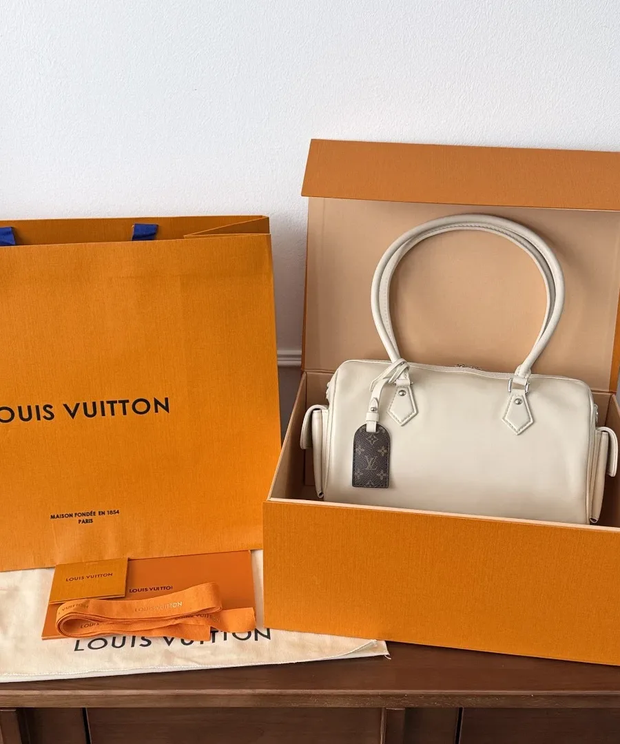 Бежевая сумка Speedy Cargo рядом с фирменной оранжевой коробкой и пакетом Louis Vuitton