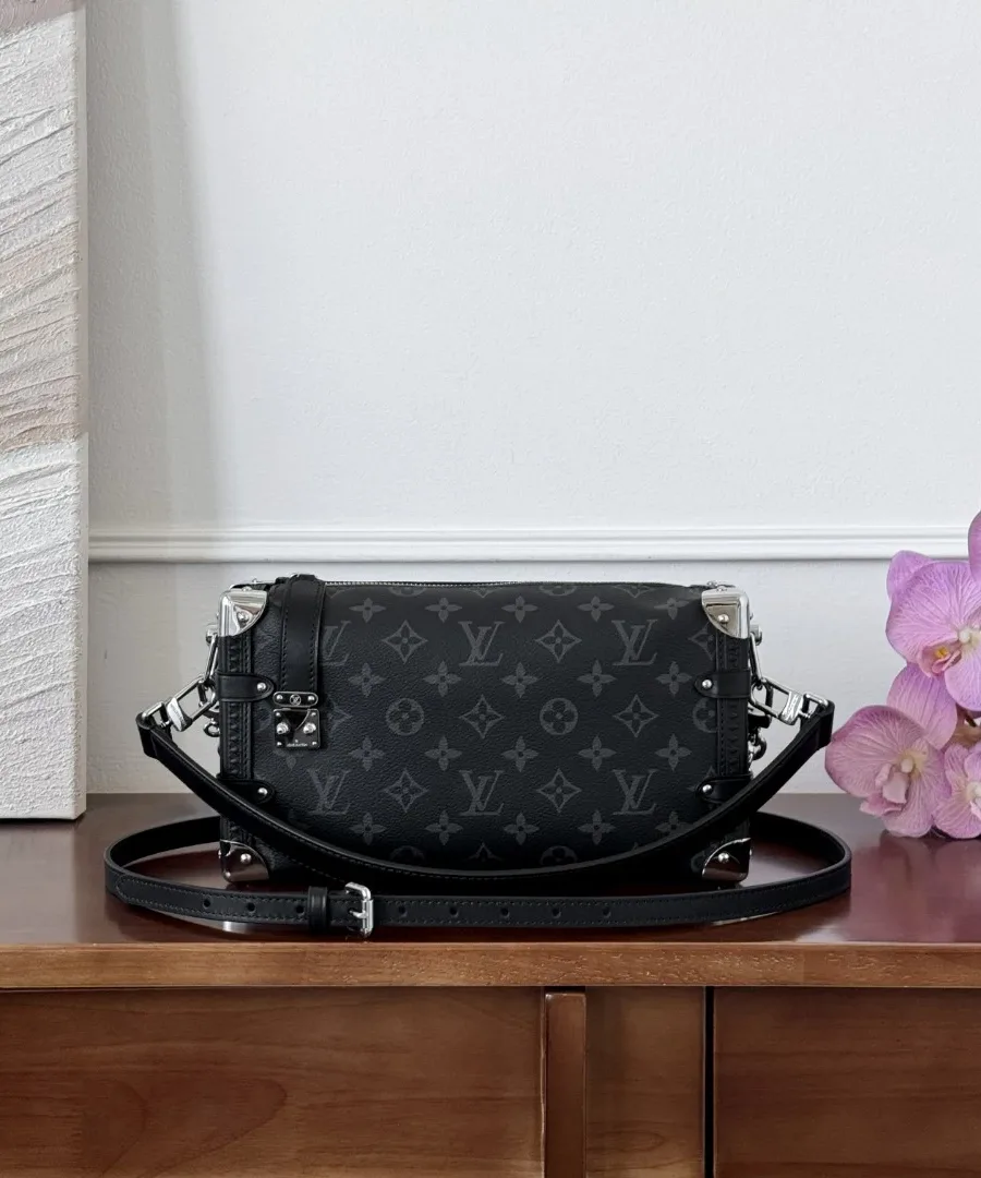 Черная сумка Louis Vuitton Side Trunk на деревянном комоде, вид спереди с кожаным ремнем