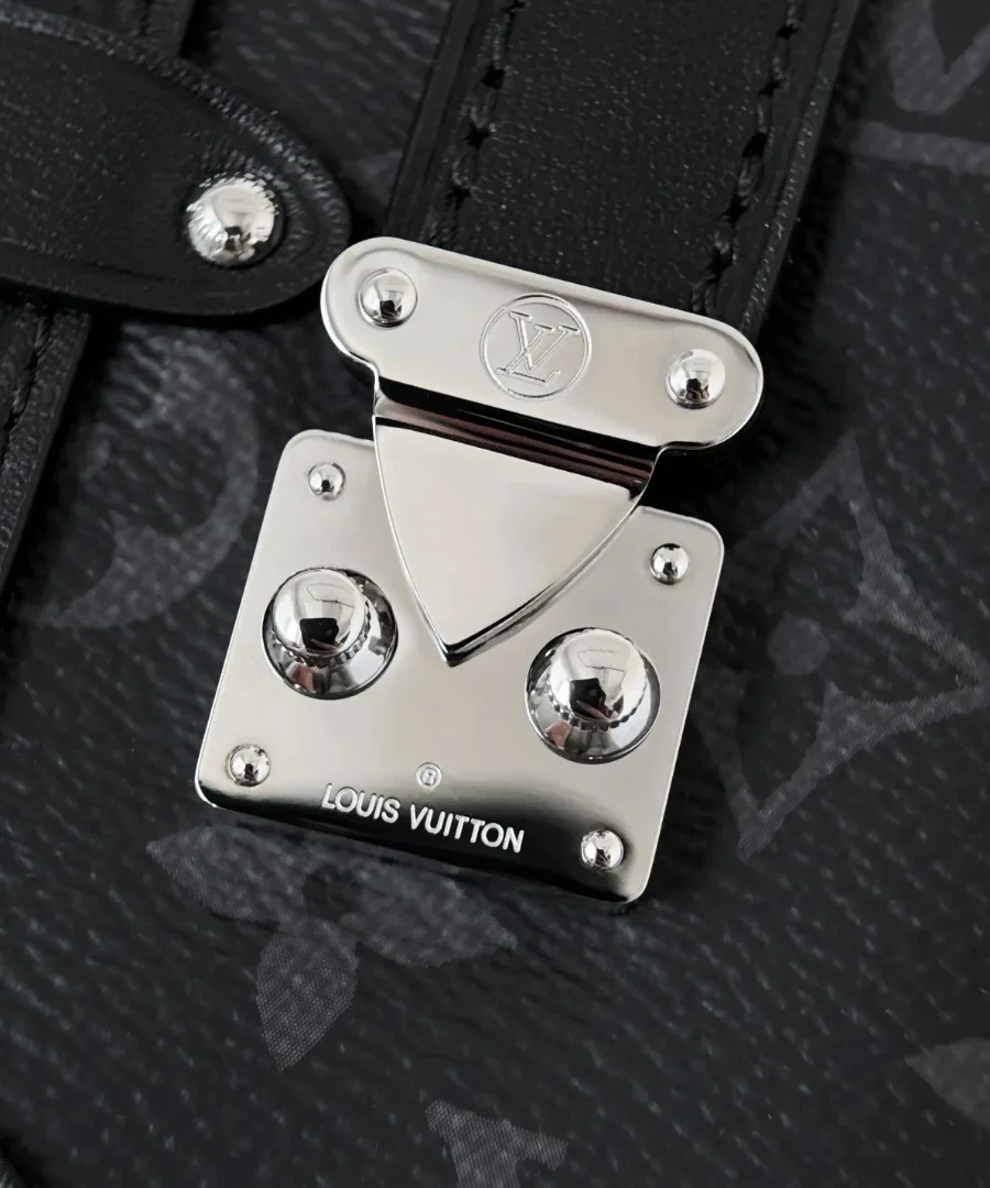 Крупный план серебристого замка S-lock с гравировкой Louis Vuitton на черной канве