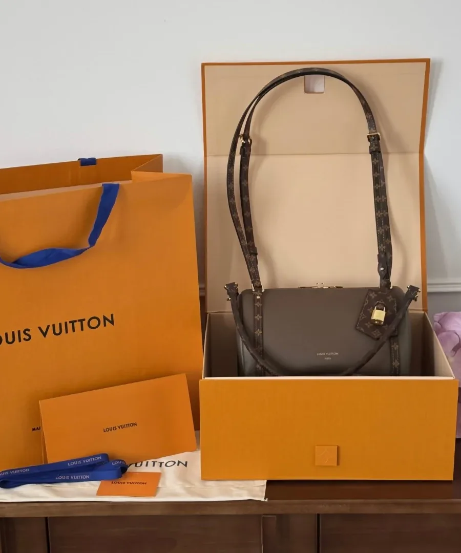 Сумка Louis Vuitton Express рядом с фирменной оранжевой коробкой и пакетом