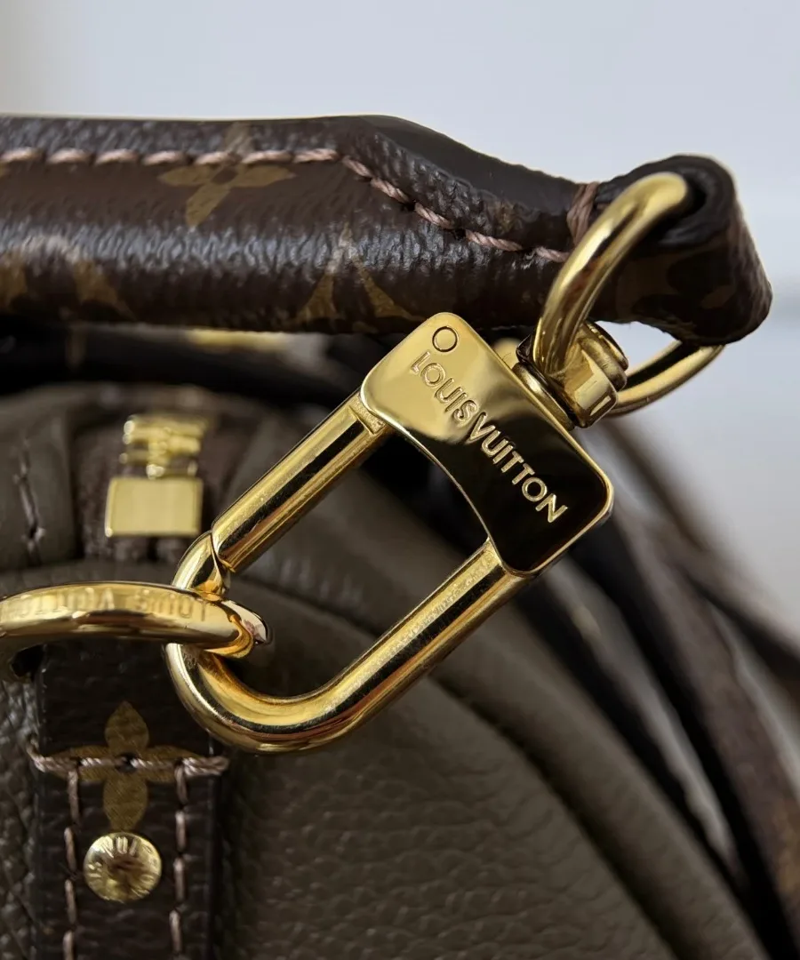 Крупный план золотистого карабина плечевого ремня с гравировкой Louis Vuitton