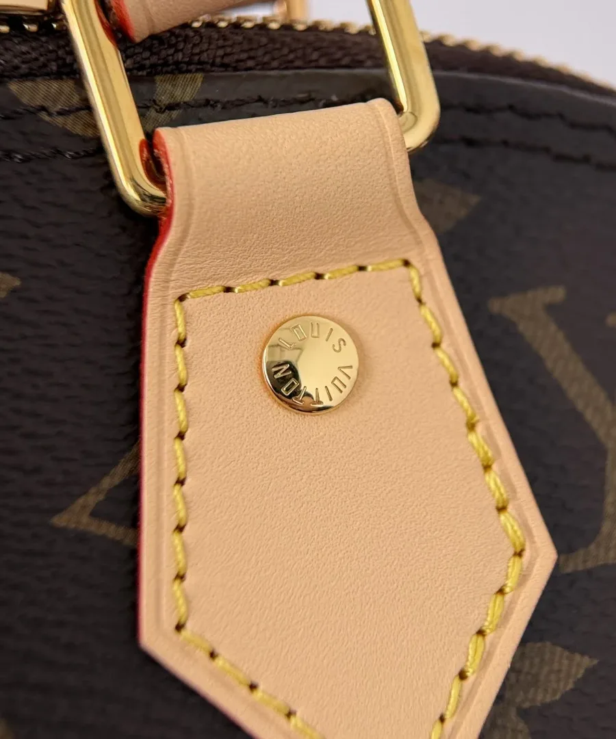 Золотистая заклепка с гравировкой Louis Vuitton на кожаном креплении ручки