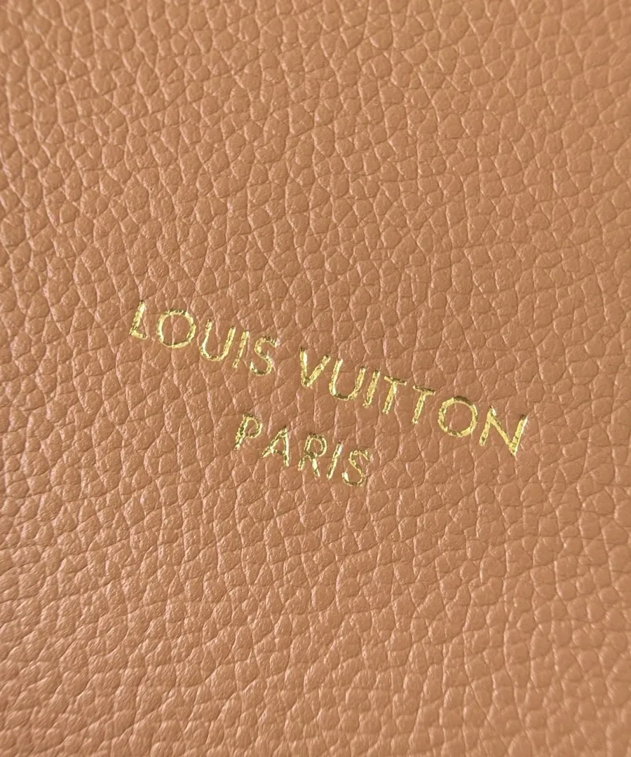 Крупный план золотистого тиснения логотипа Louis Vuitton Paris на бежевой коже