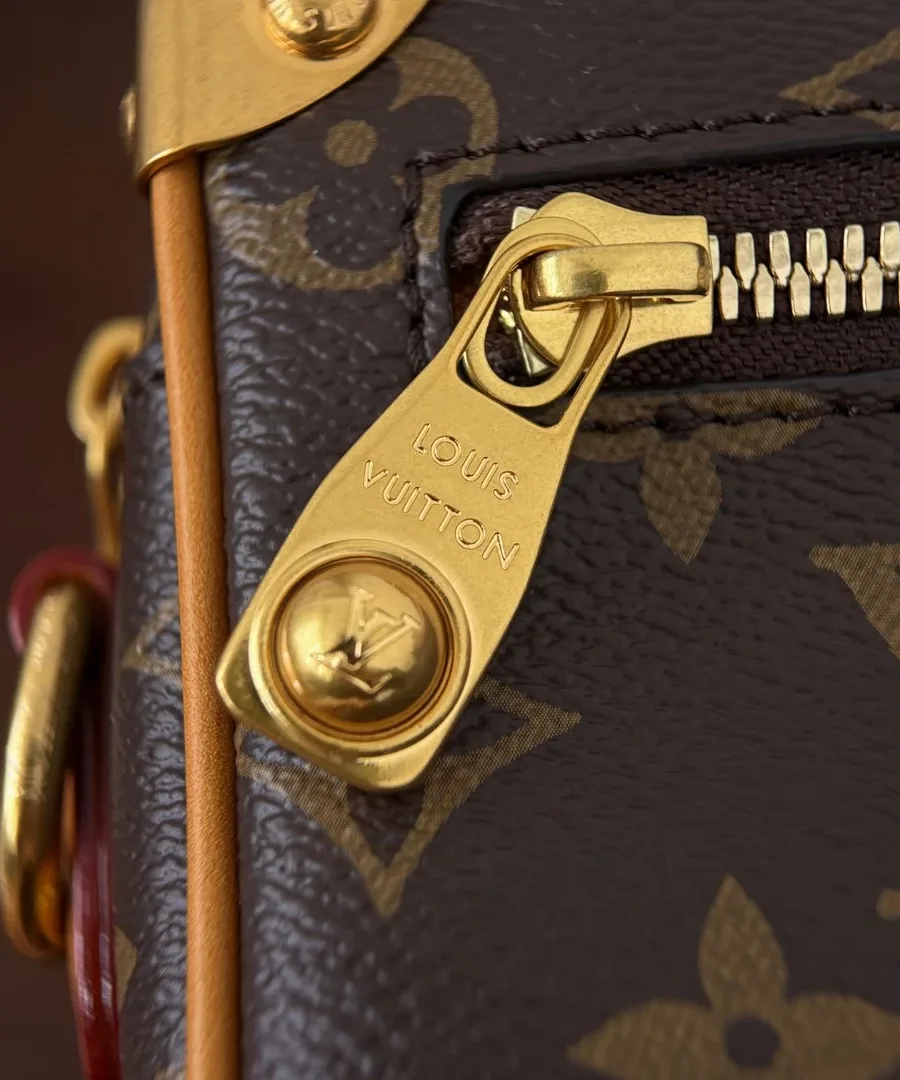 Крупный план золотистого пуллера молнии с гравировкой Louis Vuitton