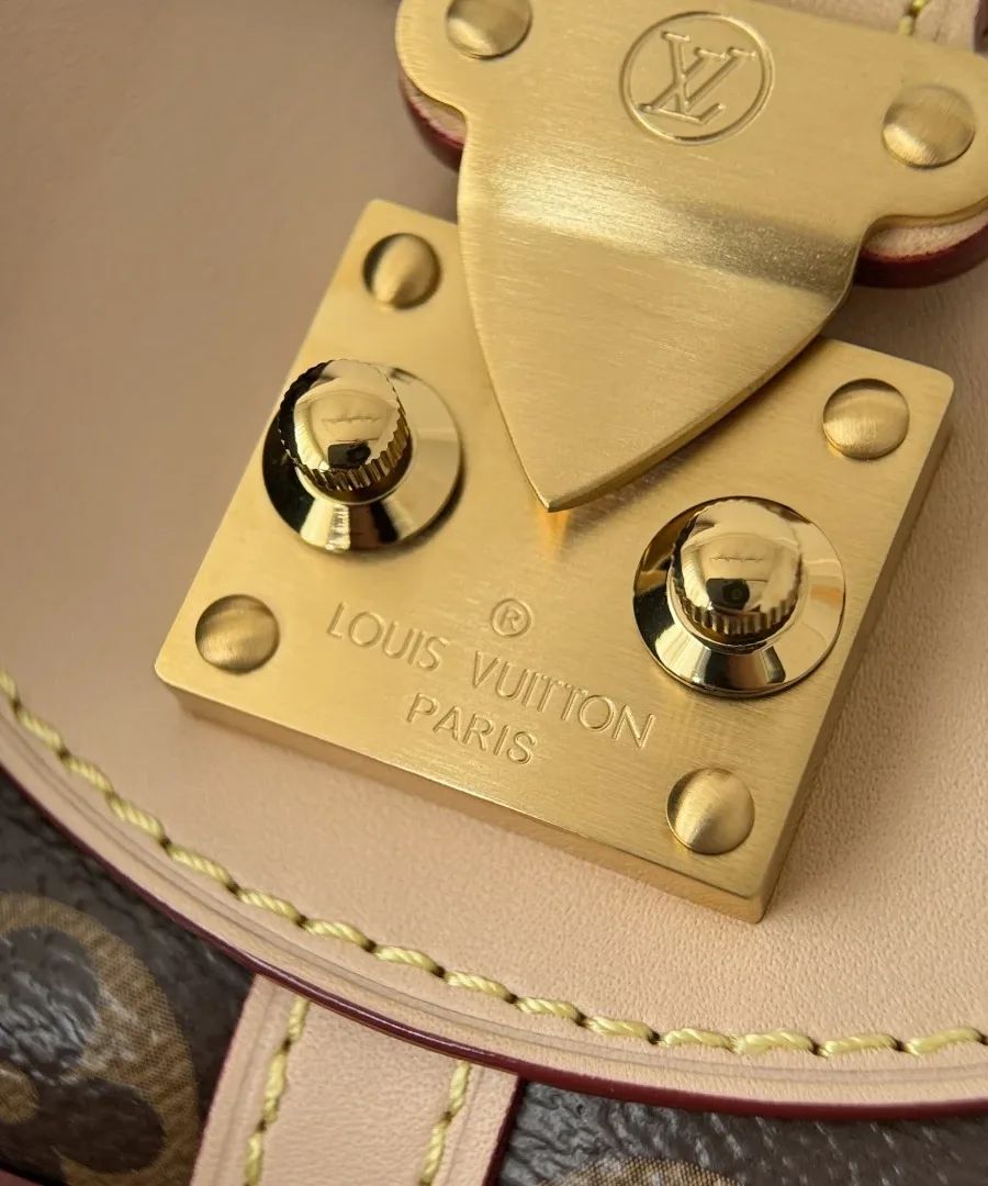 Деталь золотистой застежки с гравировкой Louis Vuitton Paris