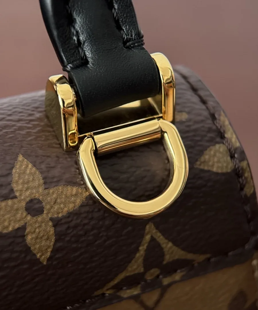 Крепление черной кожаной ручки и золотистое металлическое кольцо сумки Louis Vuitton Pico Tilsitt