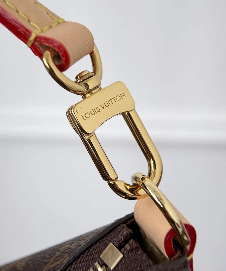 Крупный план золотистого карабина плечевого ремня с гравировкой Louis Vuitton