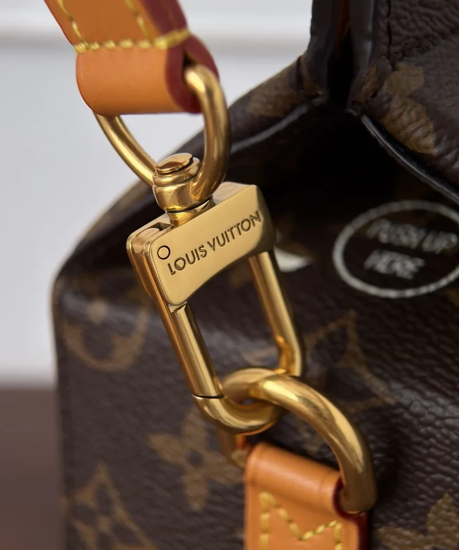 Крупный план золотистого карабина с гравировкой Louis Vuitton