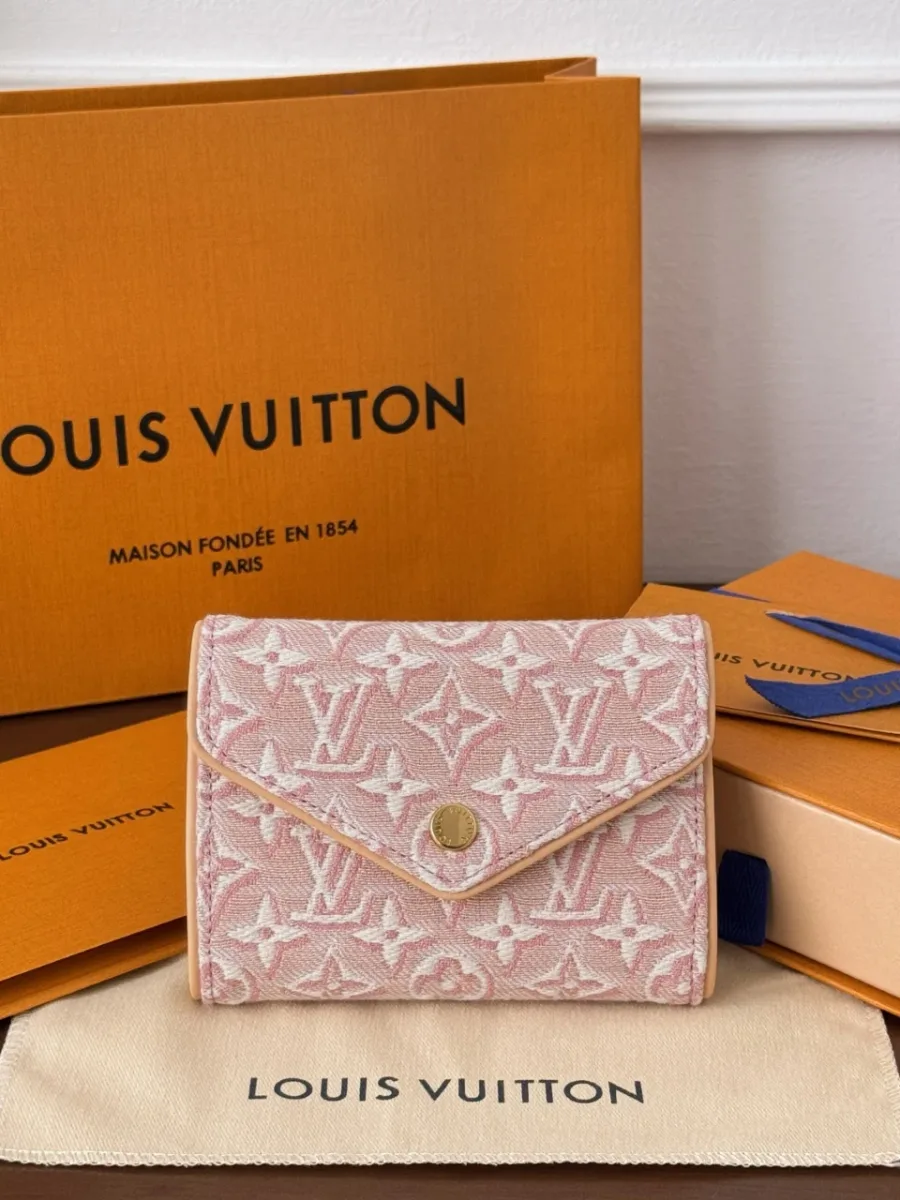 Розовый кошелек Louis Vuitton Victorine рядом с фирменной коробкой и пыльником