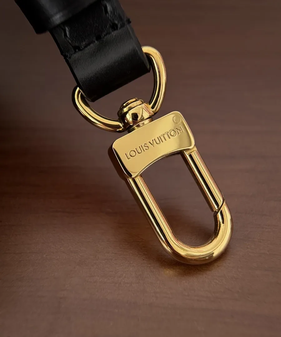 Крупный план золотистого карабина с гравировкой Louis Vuitton