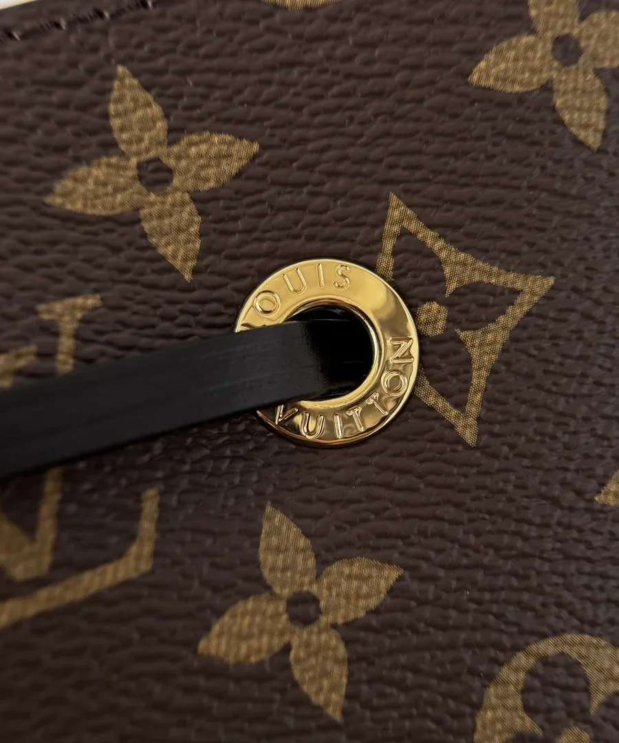 Крупный план золотистого люверса с гравировкой Louis Vuitton и чёрного шнурка