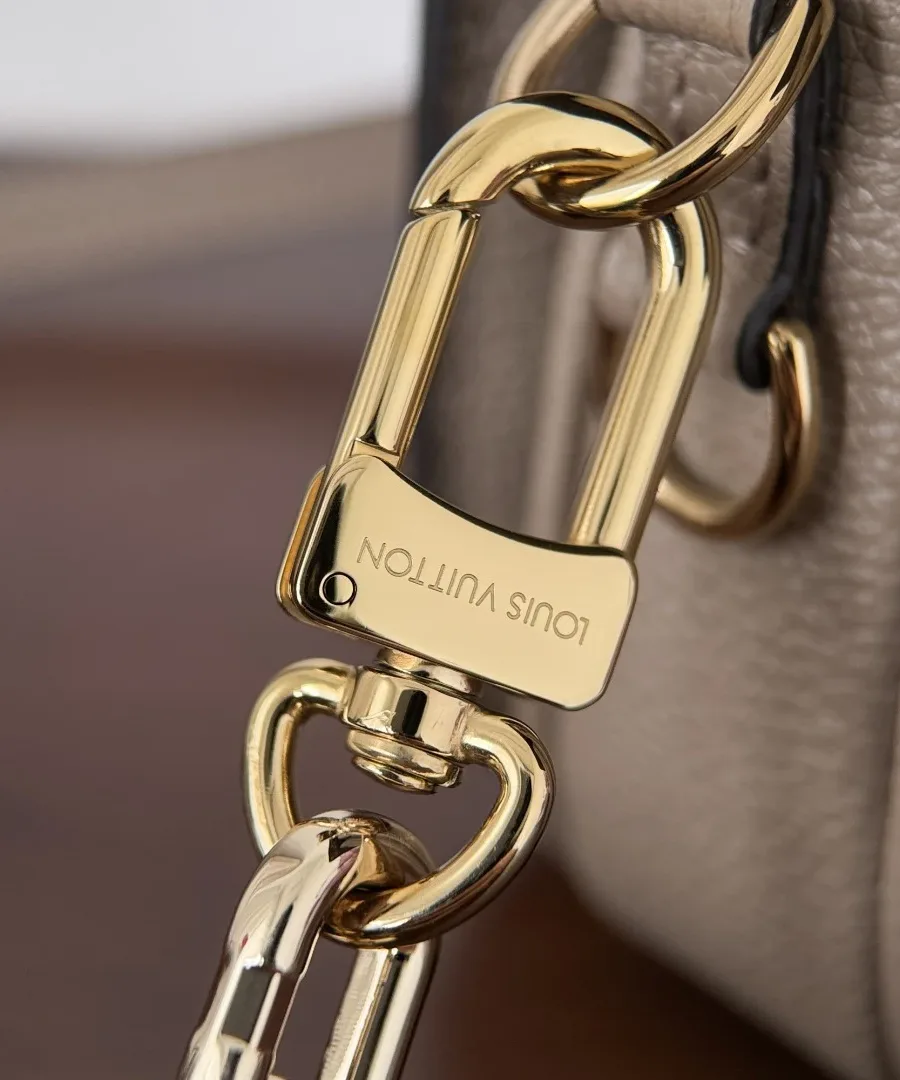 Крупный план карабина золотистой цепочки с гравировкой Louis Vuitton