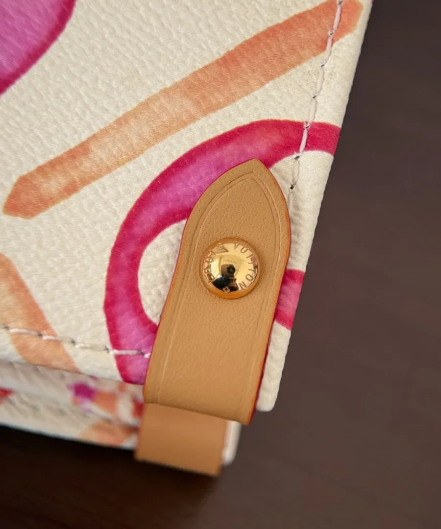 Деталь боковой кожаной застежки на кнопке сумки Louis Vuitton OnTheGo MM