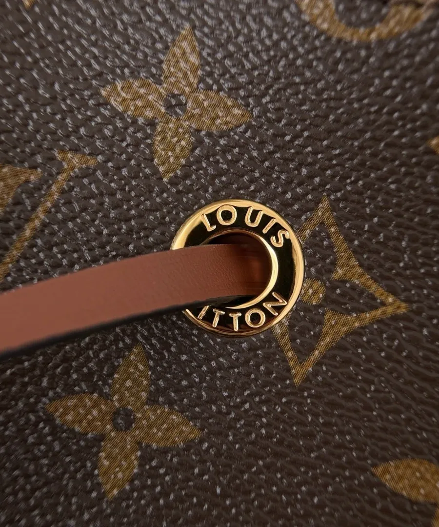 Золотистый люверс с гравировкой Louis Vuitton на коричневой канве