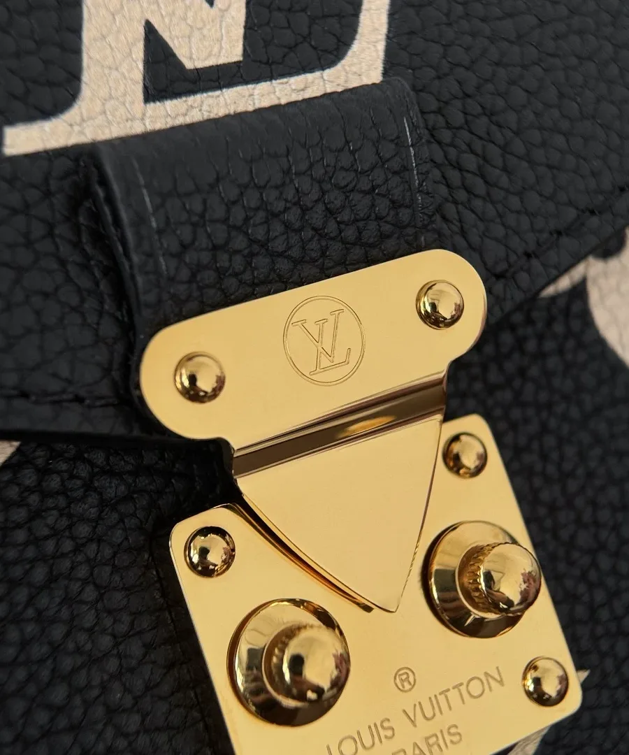 Крупный план золотистого металлического замка S-lock с гравировкой Louis Vuitton