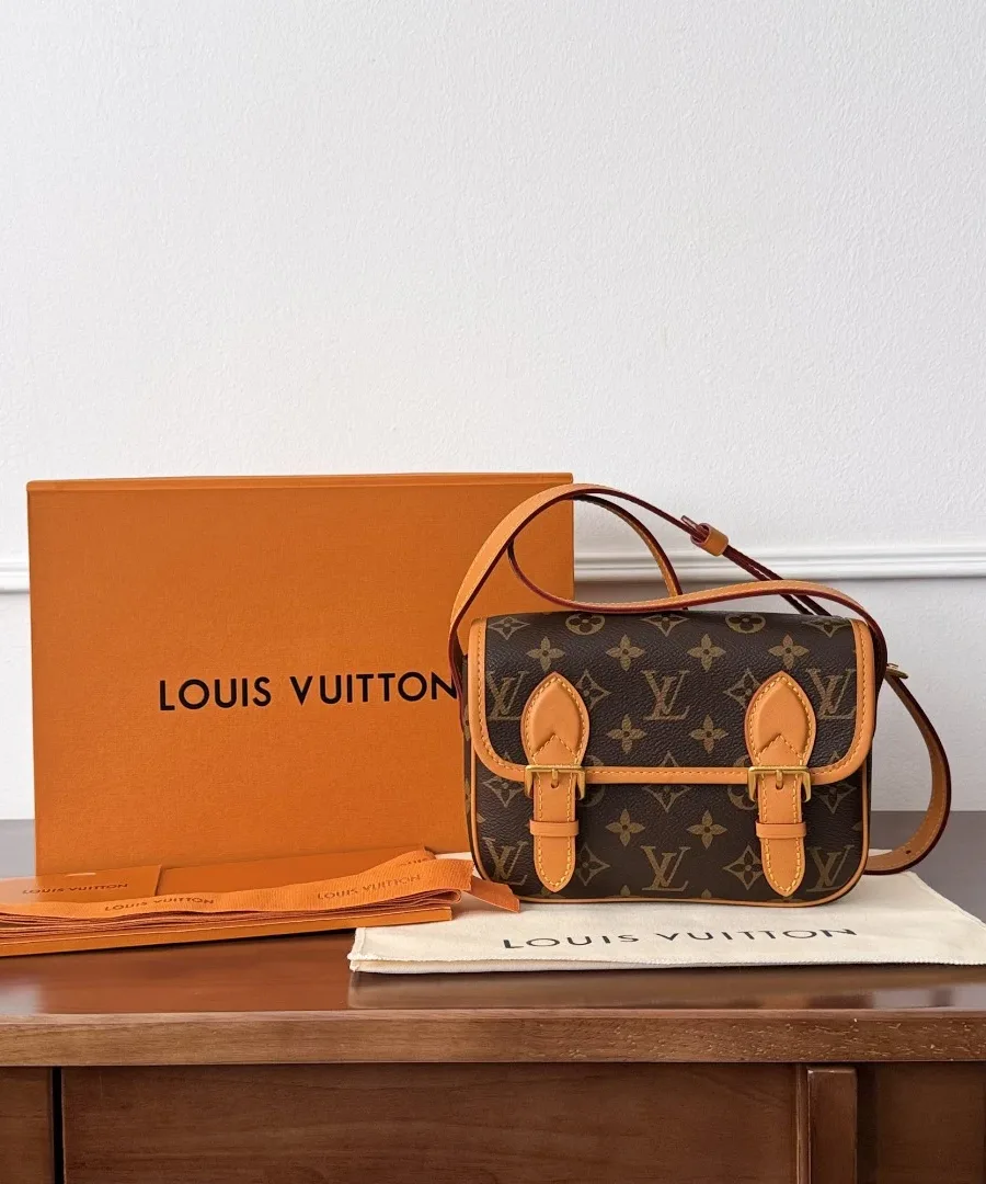 Мини-сумка Louis Vuitton Saumur Monogram рядом с фирменной оранжевой коробкой и пыльником