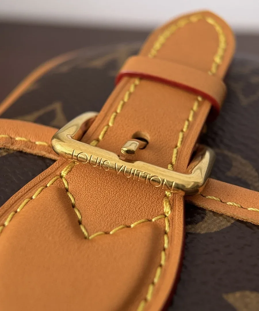 Деталь золотистой металлической пряжки с выгравированным логотипом Louis Vuitton