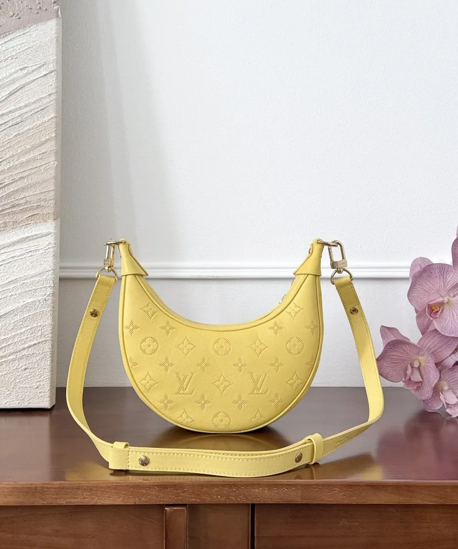 Жёлтая сумка Louis Vuitton Loop с кожаным плечевым ремнём на деревянном столе
