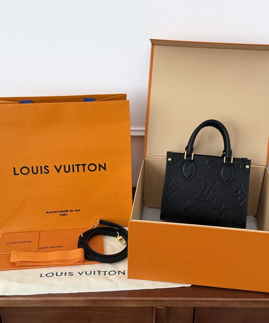 Черная сумка Louis Vuitton OnTheGo BB рядом с фирменной коробкой и пакетом
