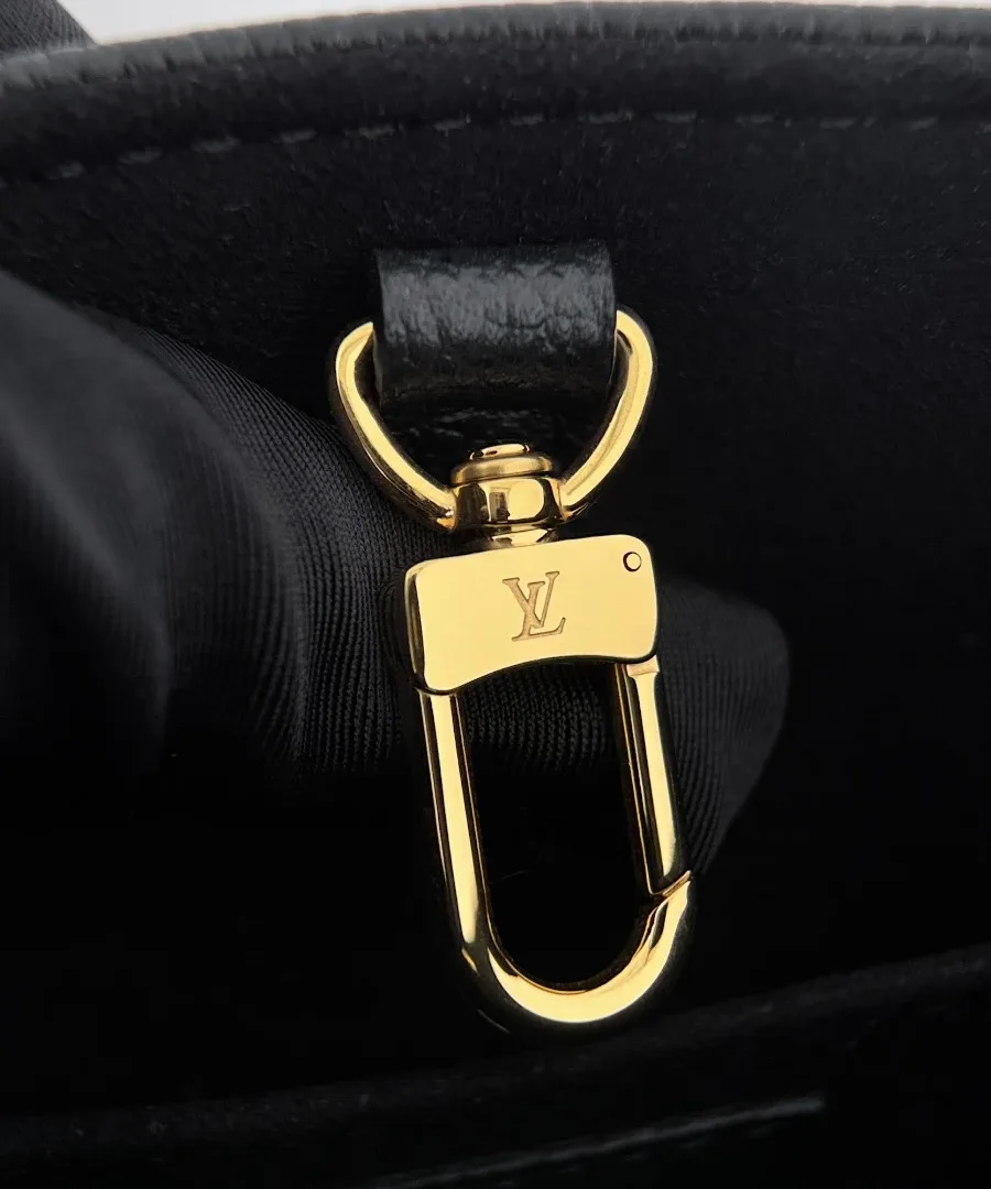 Золотистый карабин-застежка внутри черной сумки Louis Vuitton