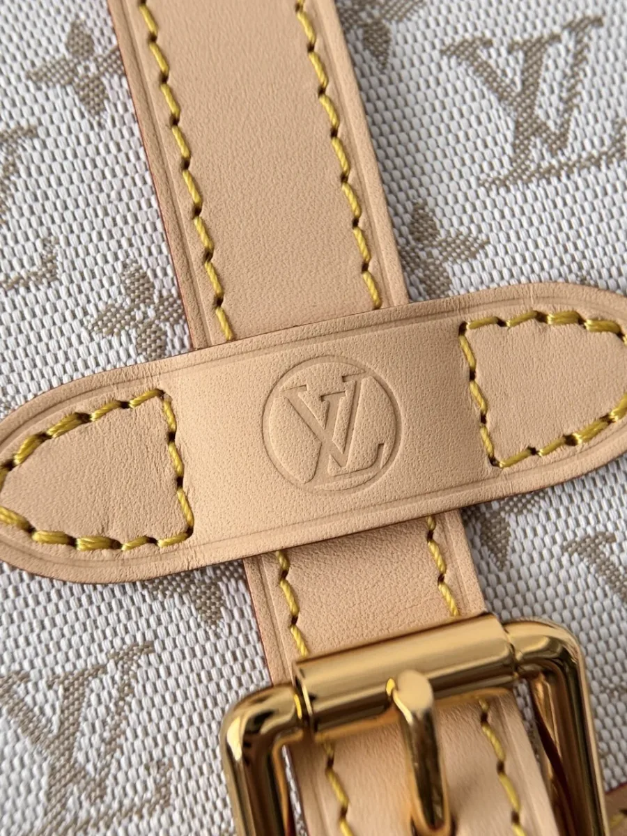 Крупный план кожаного ремешка с тиснением LV и золотистой пряжкой