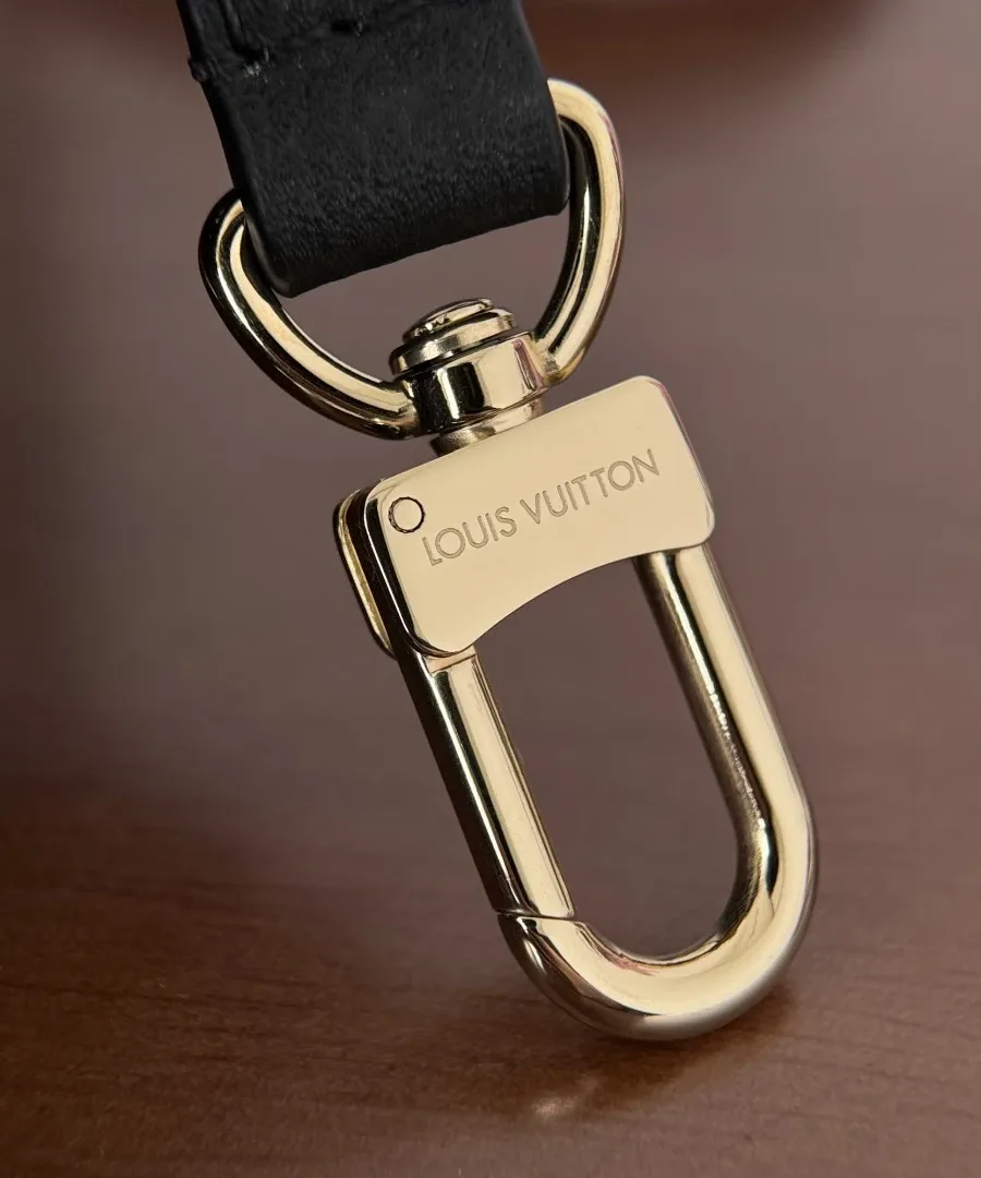 Крупный план карабина кожаного плечевого ремня с гравировкой Louis Vuitton