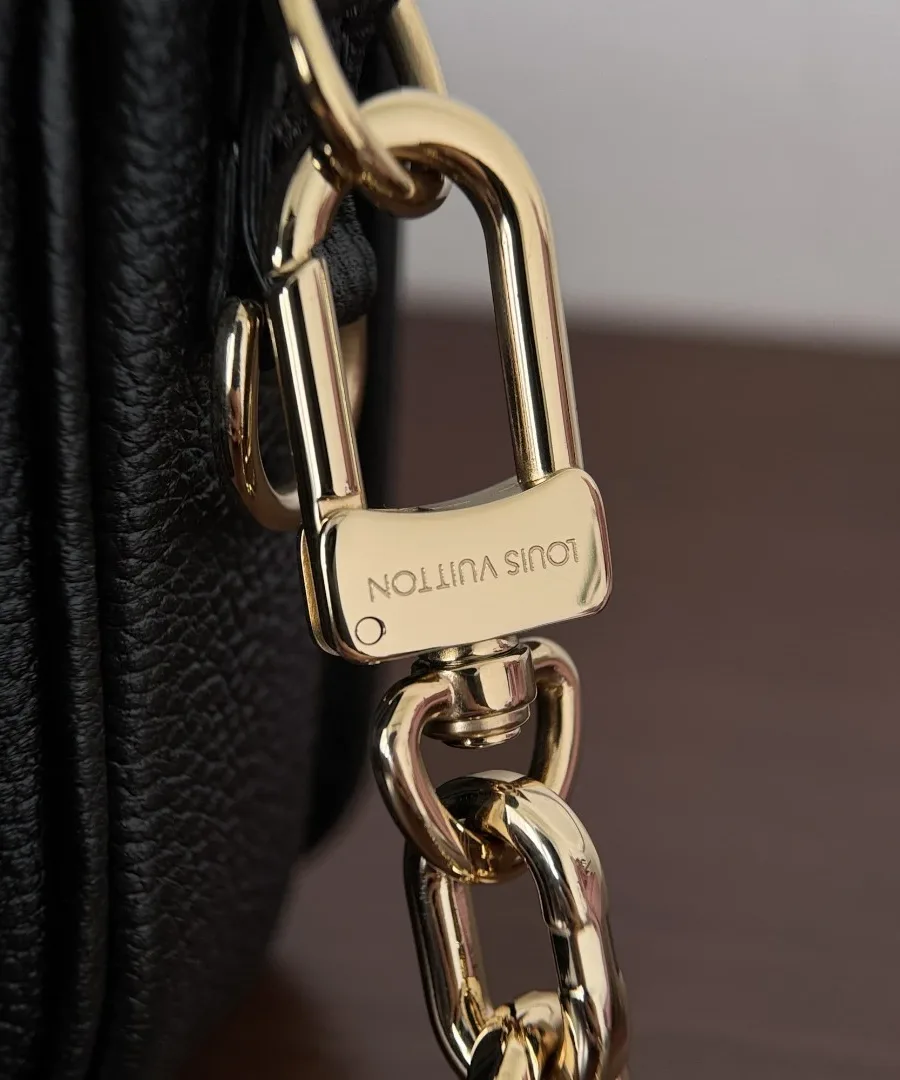 Крупный план карабина золотистой цепочки с гравировкой Louis Vuitton