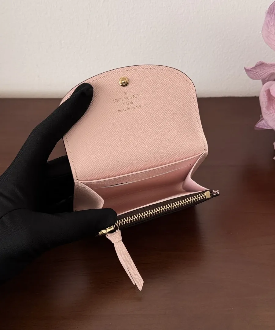 Открытый кошелек Louis Vuitton Rosalie Monogram в руке, видны розовые отделения