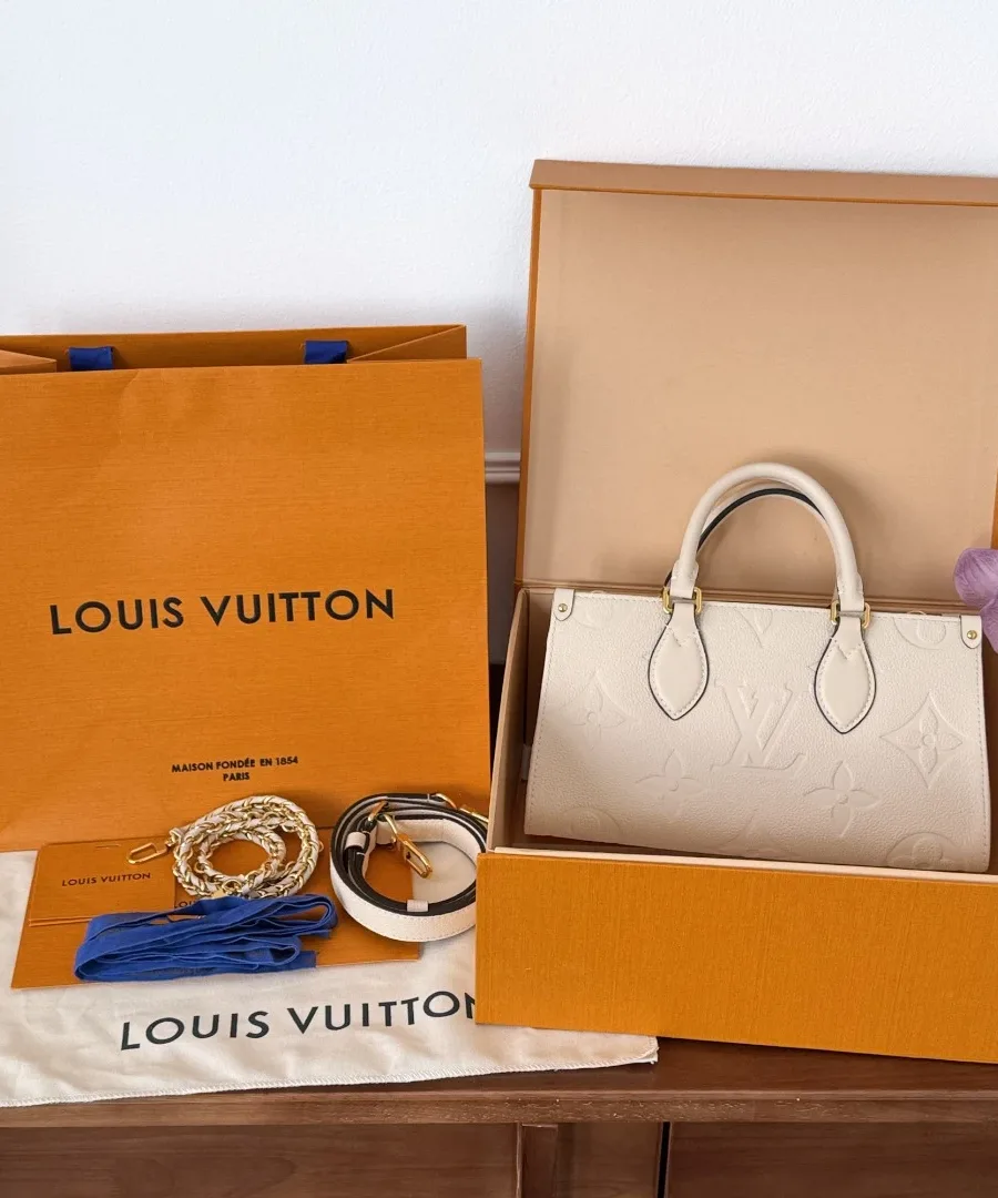 Сумка Louis Vuitton OnTheGo East West рядом с фирменной коробкой и пакетом