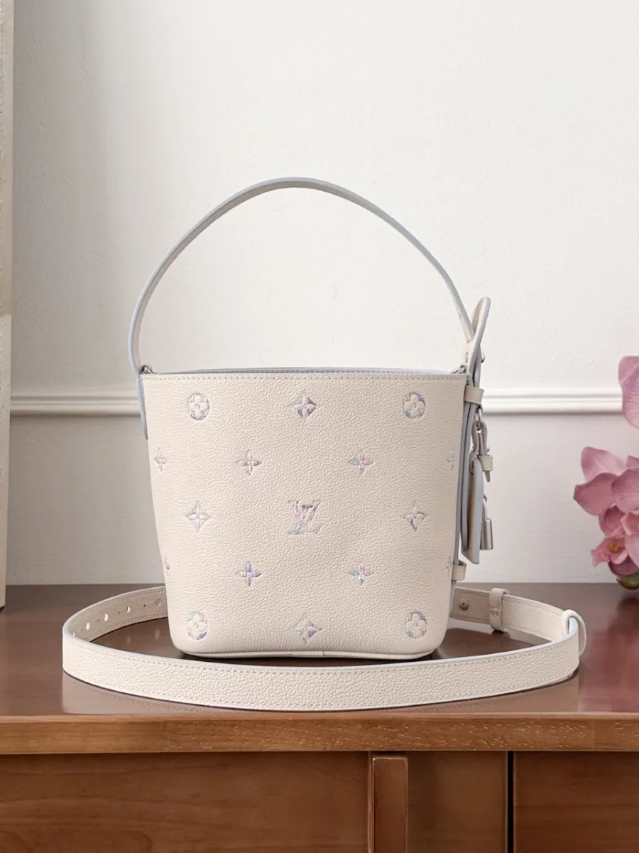 Бежевая сумка-ведро Louis Vuitton All-In BB с плечевым ремнем на деревянном столе, вид спереди