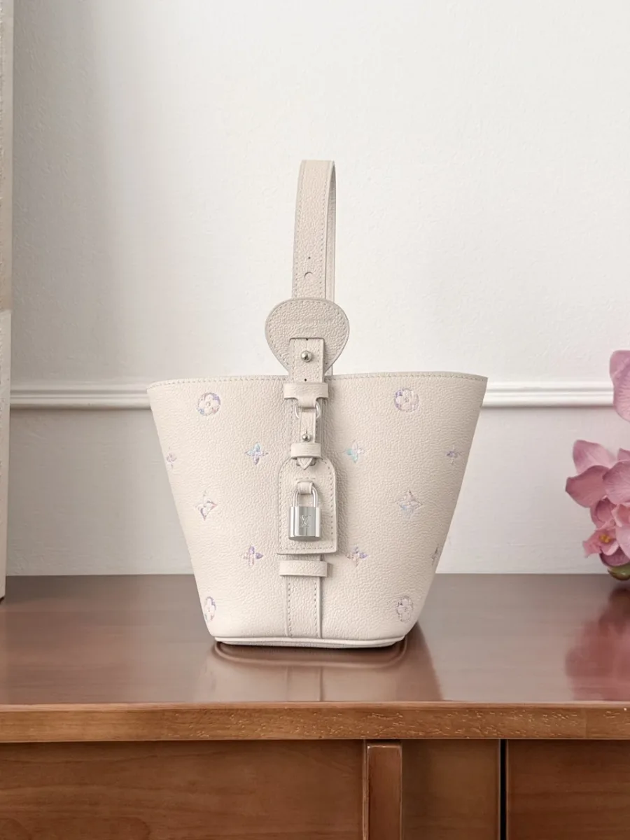 Боковая сторона бежевой сумки-ведра Louis Vuitton All-In BB с кожаным ремешком