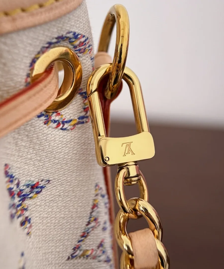 Крупный план золотистого карабина цепочки и крепления на сумке Louis Vuitton