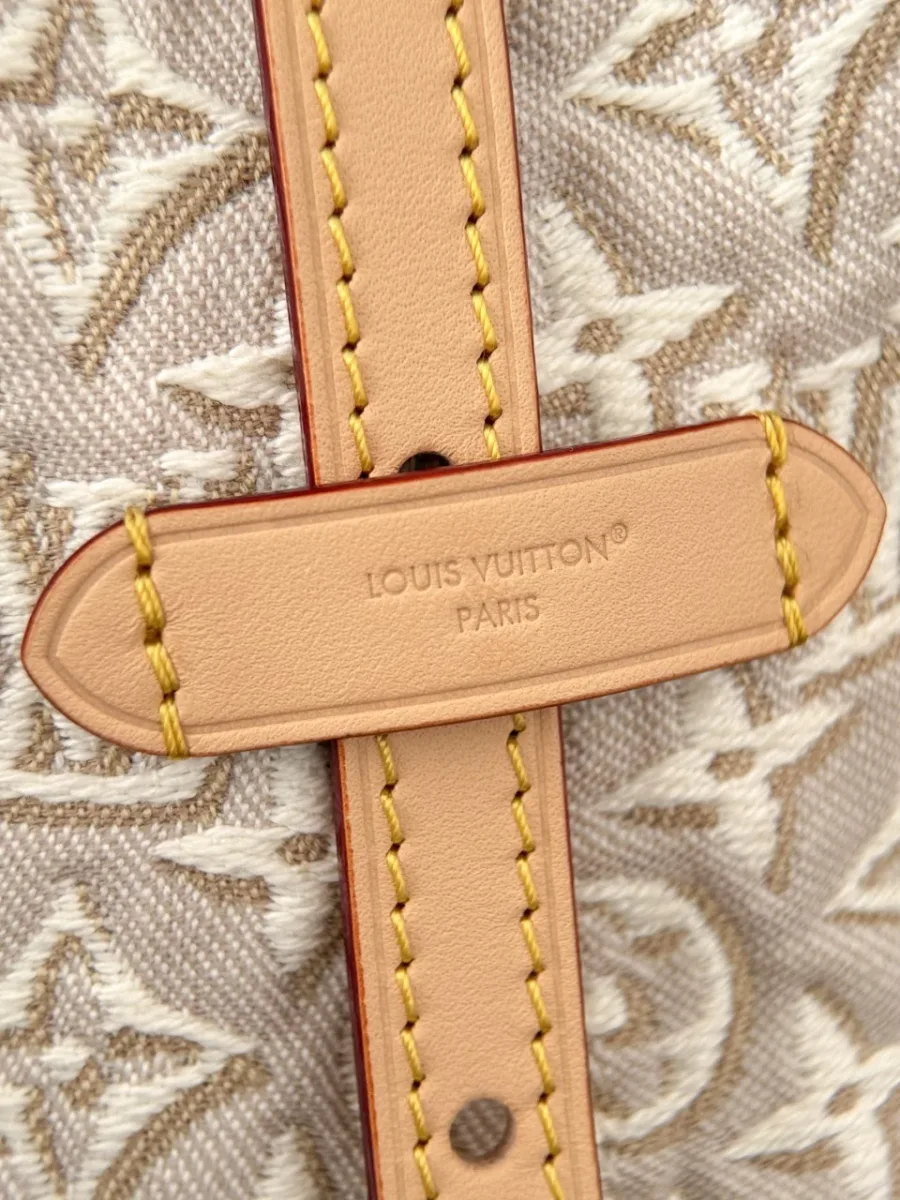 Крупный план кожаного ремешка с тиснением Louis Vuitton Paris на фоне рельефного текстиля