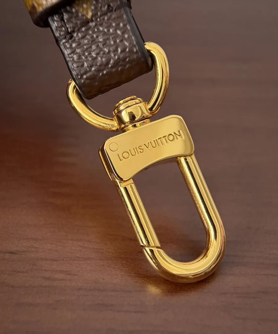 Золотистый карабин плечевого ремня с гравировкой Louis Vuitton крупным планом