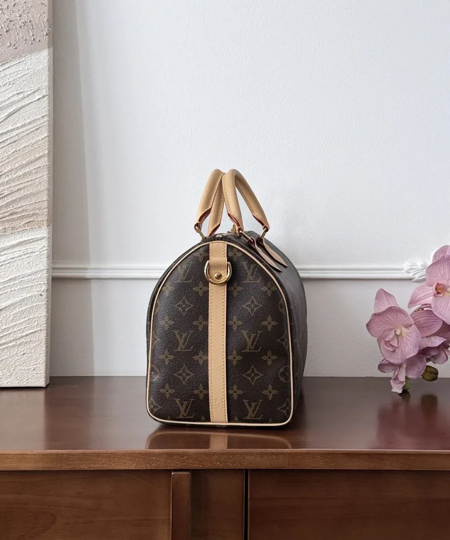 Вид сбоку на сумку Louis Vuitton Speedy 30, демонстрирующий кожаную отделку и крепление ремня