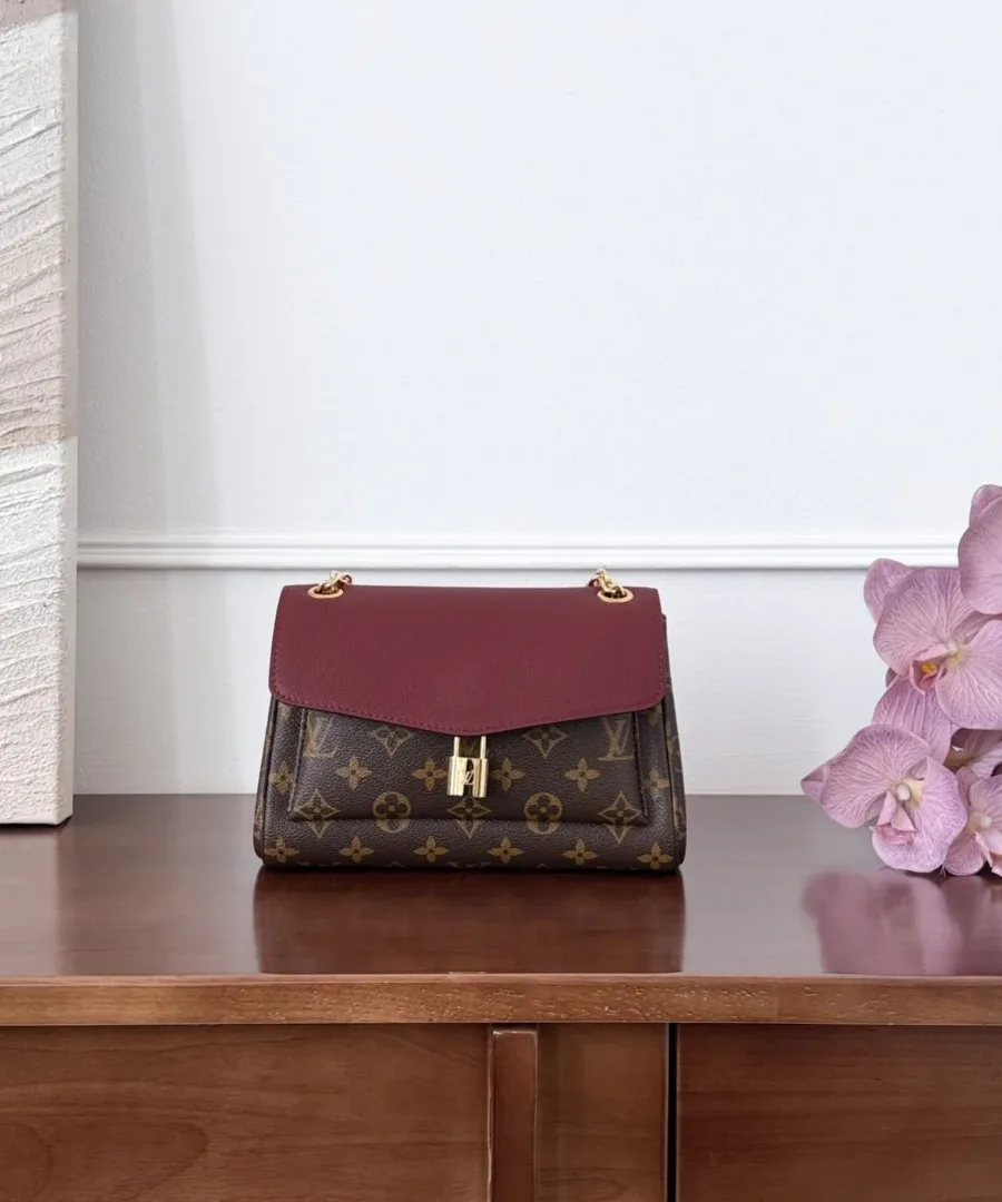 Коричневая сумка Louis Vuitton с бордовым клапаном на деревянном комоде, вид спереди