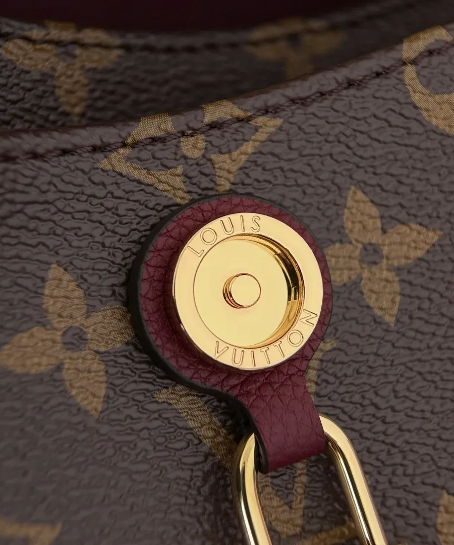 Крупный план золотистой кнопки с гравировкой Louis Vuitton